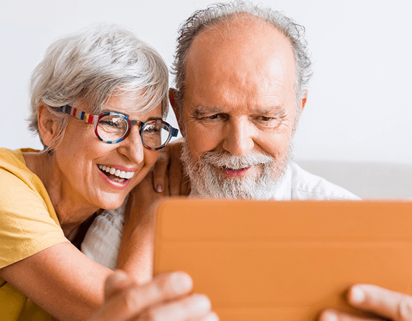 A woman and man who are older adults looking at an iPad together